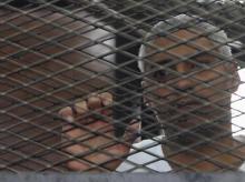 Al Jazeera journalist Mohammed Fahmy stands behind bars at a court in Cairo, May 15, 2014. PHOTO BY REUTERS/Stringer