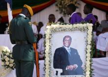 A soldier stands beside a picture of former Zimbabwean President Robert Mugabe during a church service at his rural village in Kutama, Zimbabwe, September 28, 2019. PHOTO BY REUTERS/Philimon Bulawayo