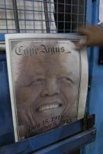 A man reaches for a copy of recently printed newspaper paying tribute to forrmer South Africa's former President Nelson Mandela at a printing press in the early hours of the morning in Cape Town