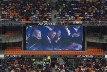 U.S. President Barack Obama (C) and his wife Michelle are seen on a big screen at the First National Bank (FNB) Stadium, also known as Soccer City, during the national memorial service for former South African President Nelson Mandela