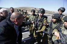 A Palestinian man argues with Israeli soldiers as they guard near the site of a fatal shooting incident next to the Palestinian village of Ein Sariya, north of the West Bank city of Ramallah