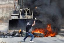 A Palestinian man hurls stones at an Israeli military machinery during clashes with Israeli troops in the West Bank village of Khobar near Ramallah, July 22, 2017. PHOTO BY REUTERS/Mohamad Torokman