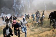 Palestinian demonstrators run for cover from tear gas fired by Israeli troops during clashes at a protest demanding the right to return to their homeland, at the Israel-Gaza border in the southern Gaza, Strip, April 27, 2018. PHOTO BY REUTERS/Ibraheem Abu Mustafa