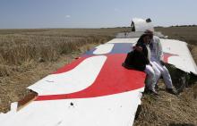 George and Angela Dyczynski sit on a piece of wreckage of the downed Malaysia Airlines Flight MH17, during their visit to the crash site