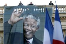 Workmen unfurl a giant banner with a photo of the late South African President Nelson Mandela to cover the facade of the Quai d'Orsay Foreign Affairs Ministry in Paris