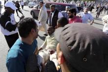 People carry a man who was injured when Libyan militiamen opened fire into a crowd of protesters