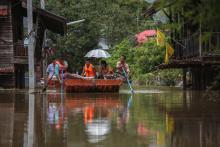 People paddle as they travel along a flooded street by boat at Kabin Buri district in Prachin Buri
