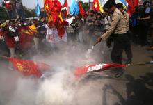 Police use a fire extinguisher to put out burning tyres during a protest by students and activists who are against a bill that would end direct elections for governors and mayors, outside parliament in Jakarta