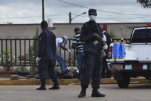 Police stand guard as officers test the body of a man for the Ebola virus, which according to police is standard protocol when bodies are discovered, in Monrovia