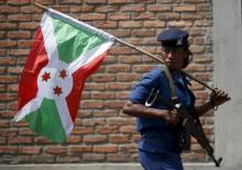 A policewoman carries a Burundi flag during a protest against President Pierre Nkurunziza's decision to run for a third term in Bujumbura, Burundi, May 29, 2015. PHOTO BY REUTERS/Goran Tomasevic