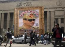 People walk past a huge banner for Egypt's army chief, Field Marshal Abdel Fattah al-Sisi in front of the High Court of Justice in downtown Cairo, March 13, 2014. Poster reads, "We love and support you. You are our president and leader". REUTERS/Amr Abdallah Dalsh