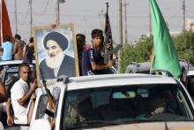 Volunteers, who have joined the Iraqi Army to fight against predominantly Sunni militants, carry weapons and a portrait of Grand Ayatollah Ali al-Sistani during a parade in the streets in Baghdad's Sadr city