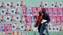Mozambicans walk past election posters ahead Tuesday's provincial and legislative elections, in Maputo, Mozambique, October 11, 2019. PHOTO BY REUTERS/Grant Lee Neuenburg