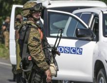 An armed pro-Russian separatist looks back next to a vehicle of the Organisation for Security and Cooperation in Europe's (OSCE) monitoring mission in Ukraine, on the way to the site in eastern Ukraine where the downed Malaysia Airlines flight MH17 crashed, outside Donetsk