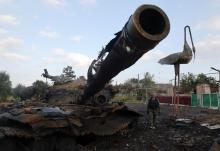 A Pro-Russian separatist walks past a destroyed tank at Savur-Mohyla, a hill east of the city of Donetsk