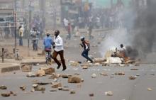 Supporters of opposition leader Kizza Besigye run in front of burned barricade in Kampala, Uganda, February 19, 2016. PHOTO BY REUTERS/Goran Tomasevic