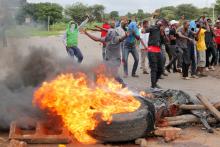 Protesters stand behind a burning barricade during protests on a road leading to Harare, Zimbabwe, January 15, 2019. PHOTO BY REUTERS/Philimon Bulawayo