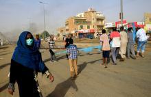 A woman walks past Sudanese protesters erecting a barricade on a street and demanding that the country's Transitional Military Council hand over power to civilians in Khartoum, Sudan June 3, 2019. PHOTO BY REUTERS/Stringer