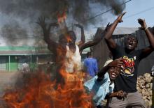 Protesters, who are against President Pierre Nkurunziza's decision to run for a third term, gesture in front of a burning barricade in Bujumbura, Burundi, May 14, 2015. PHOTO BY REUTERS/Goran Tomasevic