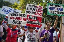 Anti-government protesters hold placards during a march through central Bangkok