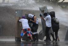 Anti-government protesters are hit by a water cannon during clashes with the national guard at Altamira square in Caracas