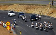 Villagers wave along the road as the funeral cortege carrying the coffin of former South African President Nelson Mandela drives through Mandela's homeland just outside the village of Qunu