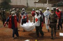 Local Red Cross workers carry a body as they move bodies from a mass grave at a military camp in the 200 villas neighbourhood of Bangui