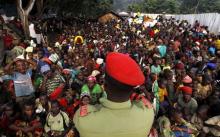 A Tanzanian policeman watches over as Burundian refugees gather on the shores of Lake Tanganyika in Kagunga village in Kigoma region in western Tanzania to wait for MV Liemba to transport them to Kigoma township, May 17, 2015. PHOTO BY REUTERS/Thomas Mukoya