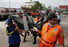Rescue team members walk as they carry the wreckage of a seat of the AirAsia Flight QZ8501 airliner at Kumai port in Pangkalan Bun, January 19, 2015. PHOTO BY REUTERS/Beawiharta