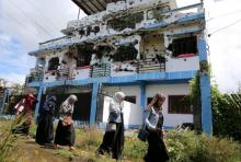 Residents who returned from evacuation centers walk past a bullet-ridden house believed to have been rented by pro-Islamic State militant group leaders Isnilon Hapilon and Omar Maute before their attack on the region, in Basak, Malutlut district in Marawi city, Philippines, October 29, 2017. PHOTO BY REUTERS/Romeo Ranoco