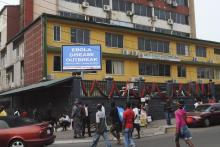 Pedestrians walk past a sign reading "Ebola disease outbreak" outside the Ministry of Finance in Monrovia, January 12, 2015. PHOTO BY REUTERS/James Giahyue