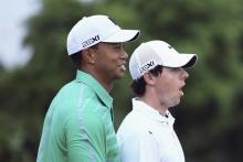 Rory McIlroy of Northern Ireland (R) reacts next to Tiger Woods of the U.S. during a 18-hole exhibition match at the Blackstone course