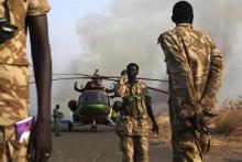 SPLA soldiers stand as a helicopter is seen after flying a trip to Bor, at Juba airport, South Sudan