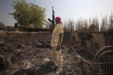 Geu Madit Kuchlong, an SPLA soldier, stands at his auntie's homestead which has been burnt and ransacked during hostilities in Bor, South Sudan