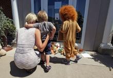 Sarah Madison (L) holds her son Beckett, 3, as her daughter Quinn, 5 (in costume), look at stuffed animals at the doorway of River Bluff Dental clinic in protest against the killing of "Cecil" a famous lion in Zimbabwe, in Bloomington, Minnesota July 29, 2015. PHOTO BY REUTERS/Eric Miller