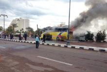 People and security officials walk and look as smoke rises from a tourist bus in the Red Sea resort town of Taba in the south Sinai