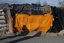 Shadows from migrants are cast on a makeshift shelter with the written word "Refugee" in Calais, France, April 30, 2015. PHOTO BY REUTERS/Pascal Rossignol