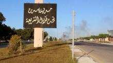 A sign which reads in Arabic, "The city of Sirte, under the shadow of Sharia" is seen as smoke rises in the background while forces aligned with Libya's new unity government advance on the eastern and southern outskirts of the Islamic State stronghold of Sirte, in this still image taken from video, June 9, 2016. PHOTO BY REUTERS