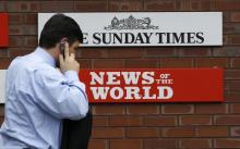 A man passes a sign outside the News International Limited complex, in London