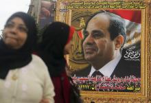 Women walk in front of a huge banner for Egypt's army chief, Field Marshal Abdel Fattah al-Sisi in downtown Cairo