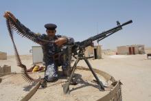 A member of the Iraqi security forces works with an ammunition belt near a weapon in the desert region between Kerbala and Najaf, south of Baghdad