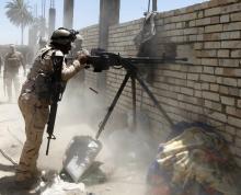 A member of the Iraqi security forces opens fire during clashes with fighters from Sunni militant group Islamic State of Iraq and the Levant (ISIL) in Ibrahim bin Ali village, west of Baghdad