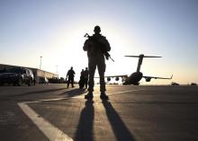 A soldier stands guard near a C-17 Globemaster III aircraft sitting on the tarmac at Kandahar Air Base