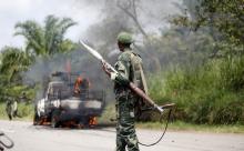 A Congolese soldier from the Armed Forces of the Democratic Republic of Congo (FARDC) looks at their burning vehicle after an ambush near the village of Mazizi in North Kivu province