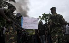 Soldiers, standing near a sign with a message against Burundian President Pierre Nkurunziza's plan to run for a third term in office, talk to protesters as they barricade a road in Bujumbura, May 8, 2015. PHOTO BY REUTERS/Jean Pierre Aime Harerimana