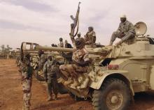 A Chadian soldier sitting on a tank, holds up his weapon ahead of his deployment in Mali, at the town of Gorou, in Niger, 10 km (6.2 miles) from Niamey