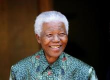 Former South African President Nelson Mandela smiles for photographers after a meeting with actor Tim Robbins at Mandela's home in Johannesburg