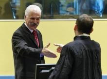 Former high ranking Bosnian Serb official Stojan Zupljanin (L) shakes hands with his lawyer in the court room as he attends trial at the International Criminal Tribunal for the former Yugoslavia in The Hague, March 27, 2013. PHOTO BY REUTERS/Michael Kooren