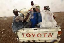 Gold mine workers at the back of a truck take cover from rain as they make their way to a local mine in Al-Ibedia locality at River Nile State