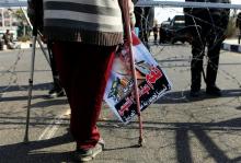 A supporter of Egypt's army chief Field Marshal Abdel Fattah al-Sisi stands on crutches in front of riot police outside a police academy, where the trial of ousted Egyptian President Mohamed Mursi and members of the Muslim Brotherhood is being conducted